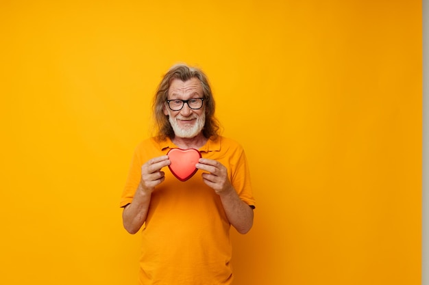 Portrait elderly man yellow tshirt and glasses posing heartshaped box cropped view