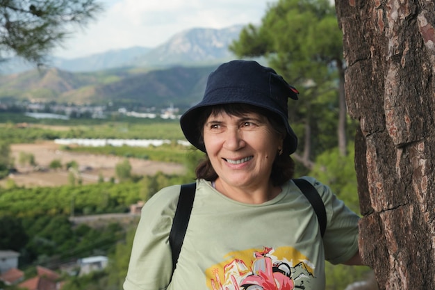 Portrait of an elderly woman in panama against a mountain landscape