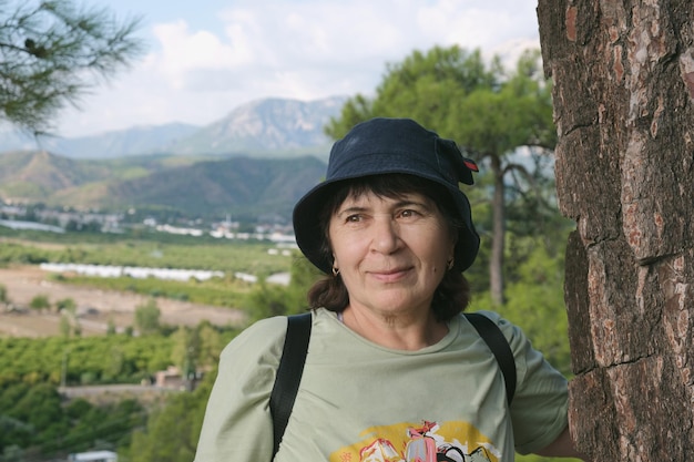 Portrait of an elderly woman in panama against a mountain landscape