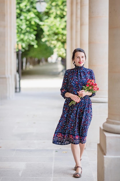 Portrait of elegant woman in a blue dress posing next to a city building