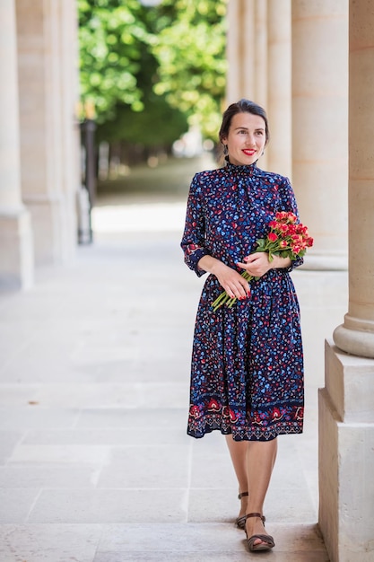 Portrait of elegant woman in a blue dress posing next to a city building