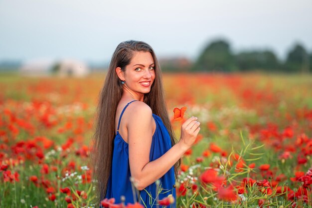 Portrait of elegant young woman in poppy field in evening sunlight