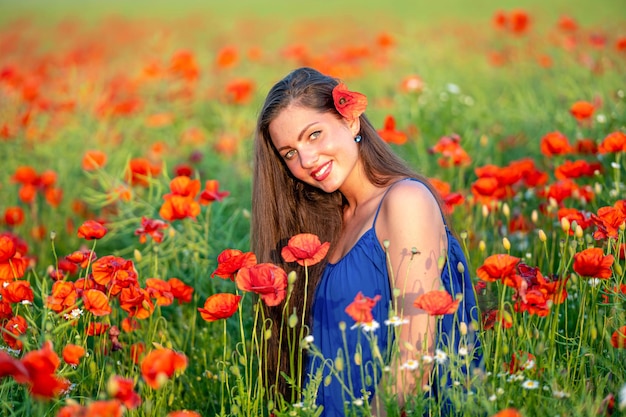 Portrait of elegant young woman in poppy field in evening sunlight