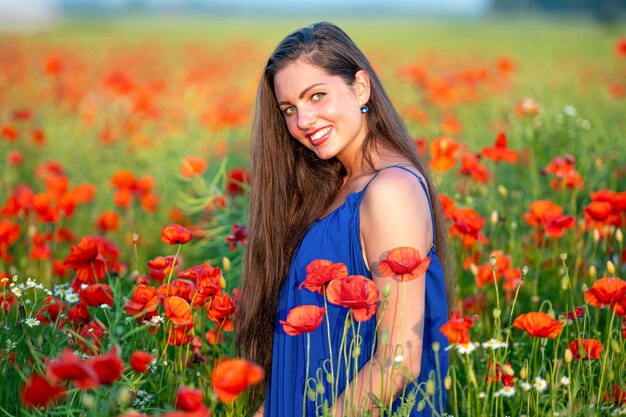 Portrait of elegant young woman in poppy field in evening sunlight