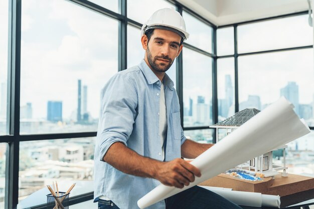 Photo portrait of engineer looking at camera while reading project plan tracery