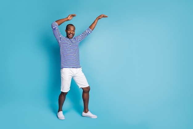 Portrait of enthusiastic afro american guy dance crazy raise hands 