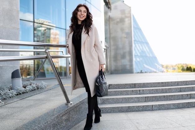 Portrait of a european woman model in a coat on the background of a business center