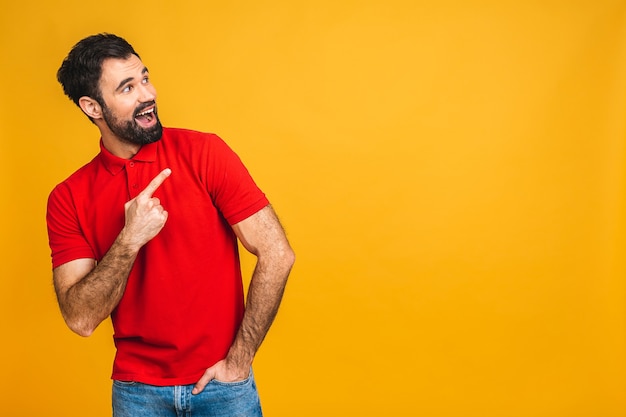 Portrait of an excited bearded happy man pointing finger up at copyspace isolated on yellow background. Copy space.