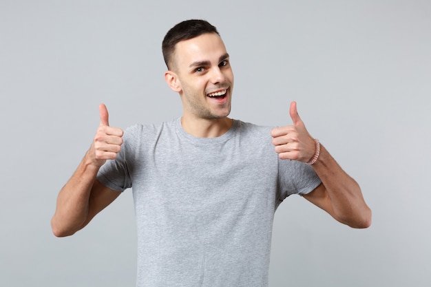 Portrait of excited funny young man in casual clothes standing showing thumbs up 