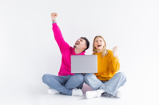 Portrait of an excited joyful couple holding laptop computer