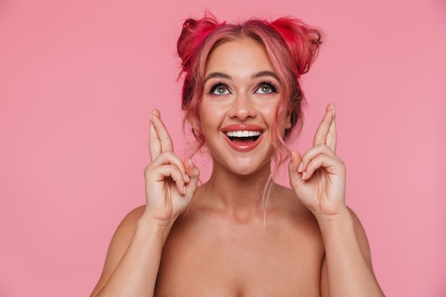 Portrait of excited shirtless young woman keeping fingers crossed and wishing good luck