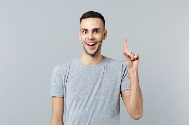 Portrait of excited young man in casual clothes, holding index finger up with great new idea