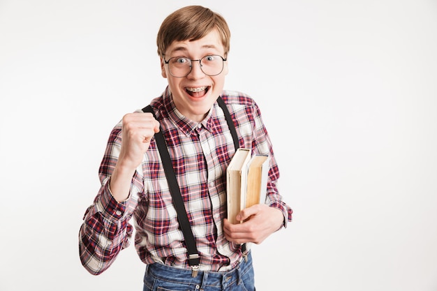 Portrait of an excited young school nerd guy holding book