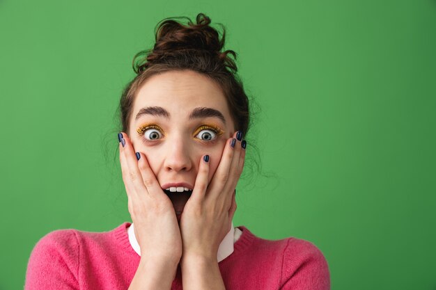 Portrait of an excited young woman screaming isolated over green