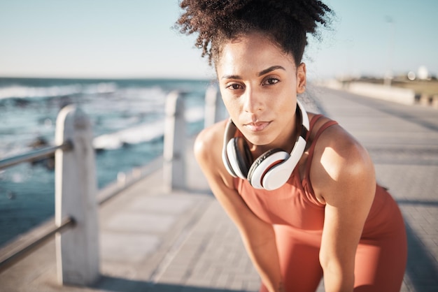 Photo portrait exercise and black woman rest beach and training outdoor headphones and wellness african american female tired lady and runner with headset exhausted and workout for cardio and seaside