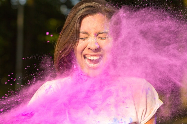 portrait of expressive woman with long hair playing with purple Holi paint