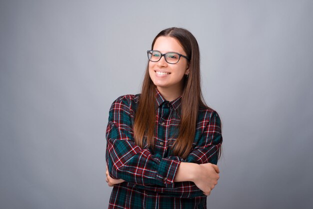 Portrait f young woman with crossed arms looking away over white wall