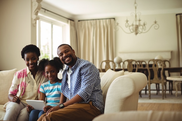 Portrait of family using digital tablet in living room