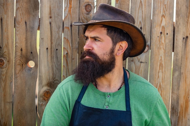 Portrait of farmer Bearded gardener on wooden background Handsome man spend time in the farm Worker