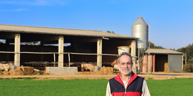 Portrait of a farmer in the countryside with a farm at sunset 