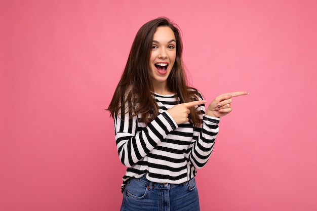 Portrait of  fascinating emotional positive joyful happpy female promoter pointing to the