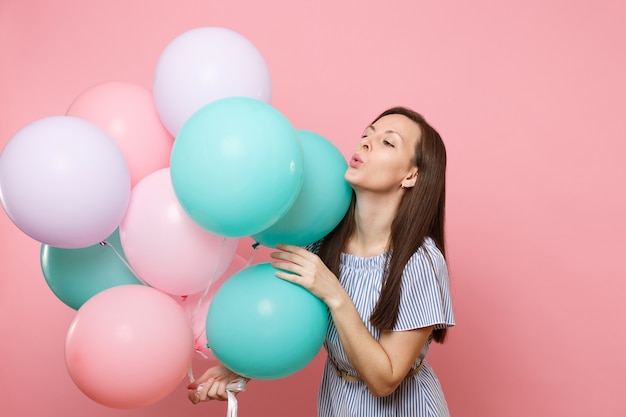 Portrait of fascinating young tender woman wearing blue dress holding colorful air balloons isolated on bright trending pink background. Birthday holiday party, people sincere emotions concept.