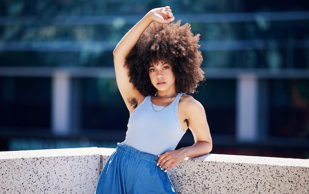 Portrait fashion and trendy with a black woman in the city on a bridge looking relaxed during summer Street style or urban and a natural young female posing outside with an afro hairstyle