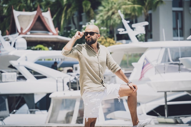 Portrait of a fashion young man posing at marina and yahts background