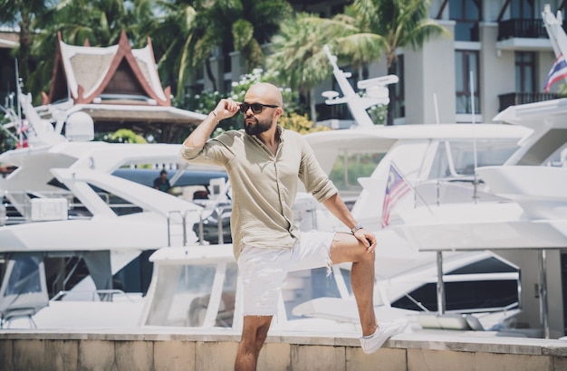 Photo portrait of a fashion young man posing at marina and yahts background