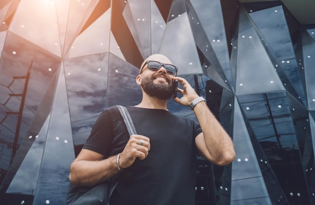 Portrait of a fashion young man talking by the phone at beautiful dark urban background