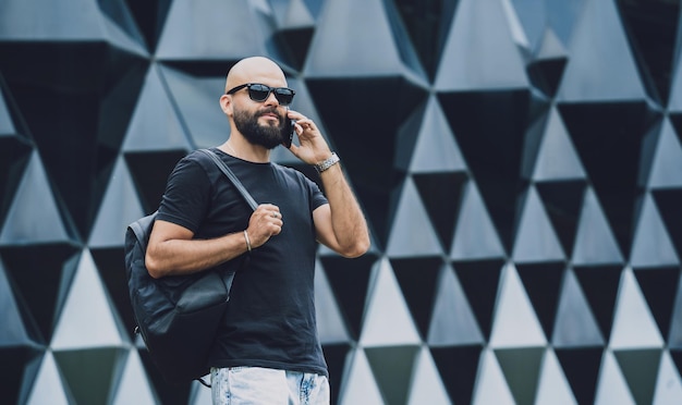 Portrait of a fashion young man talking by the phone at beautiful dark urban background