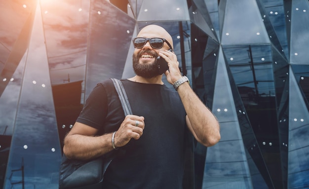 Portrait of a fashion young man talking by the phone at beautiful dark urban background