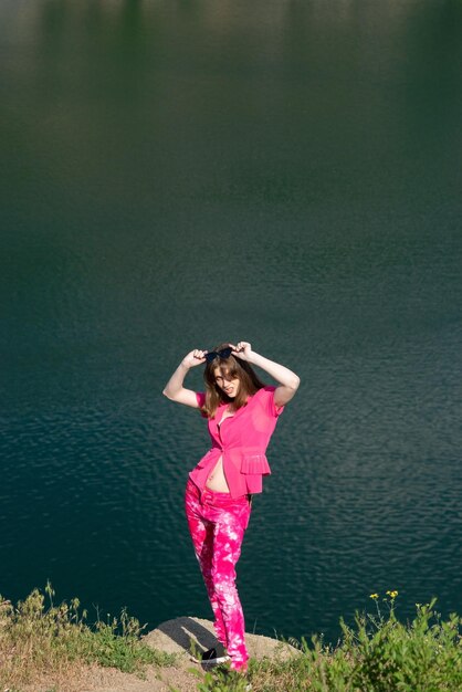 Portrait of a fashionable beautiful young girl in pink generation z Against the background of the lake water