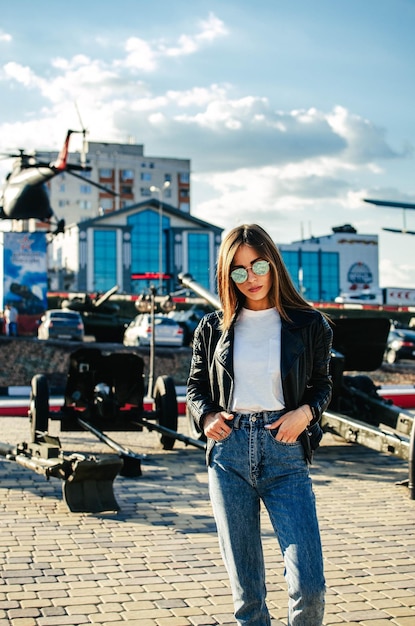 Portrait of a fashionable young woman with sunglasses at the airfield on the background of airplanes