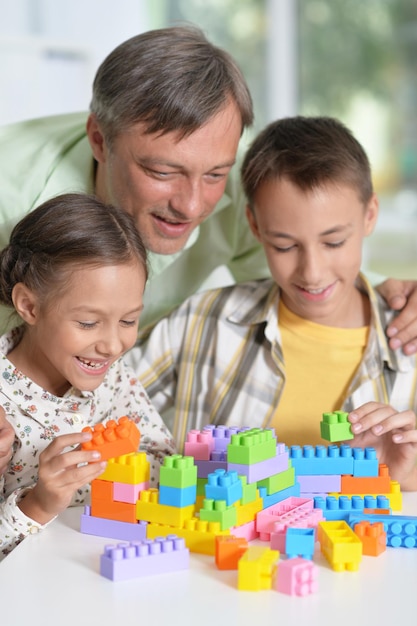 Portrait of father and children playing with colorful plastic blocks