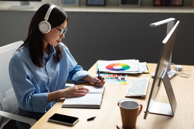 Portrait of female asian designer writing in notebook