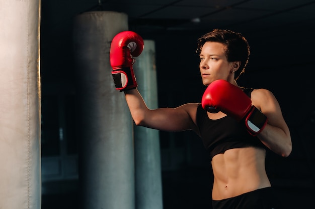 Portrait of a female boxer in red gloves in the gym during training