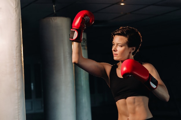 Portrait of a female boxer in red gloves in the gym during training