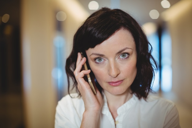 Portrait of female business executive talking on mobile phone in corridor