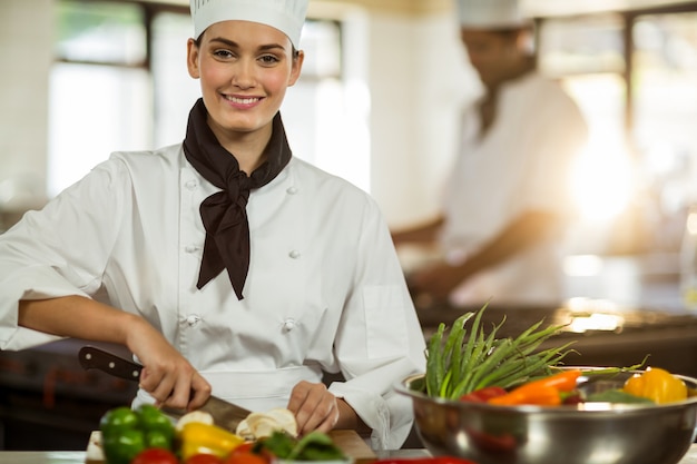 Portrait of female chef cutting vegetables