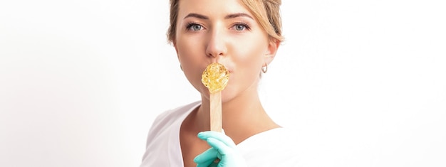 Portrait of female cosmetologist holds a wooden stick with a wax covering her lips