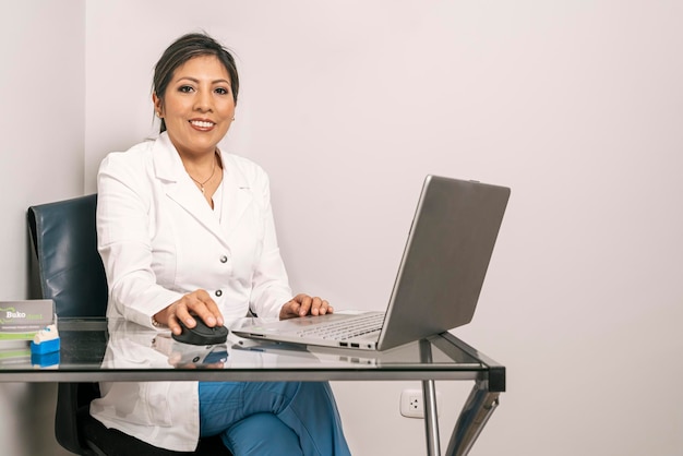 Portrait of a female dentist sitting in an office working at the laptop