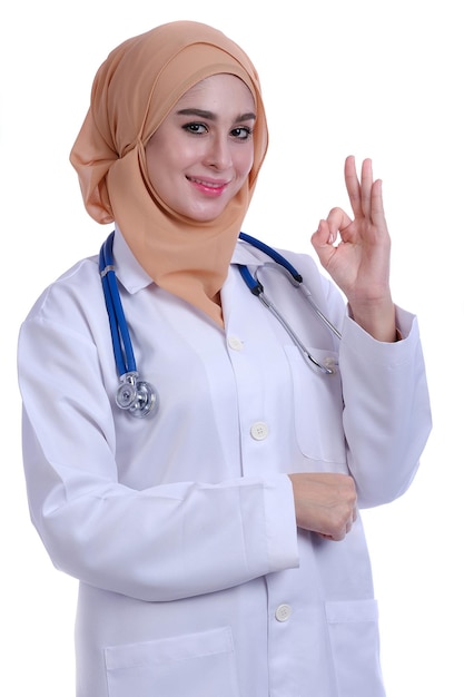 Portrait of female doctor in hijab gesturing ok sign against white background