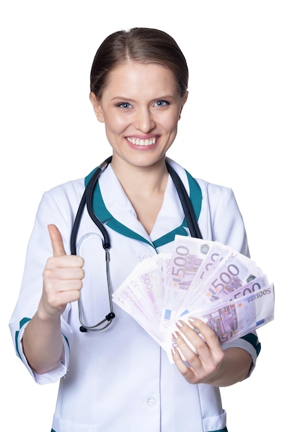 Portrait of female doctor holding money and showing thumb up isolated on white background