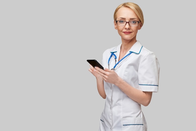 Portrait of a female doctor or nurse holding and using mobile phone