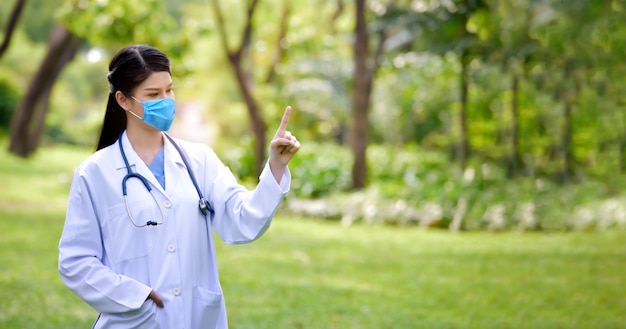 Portrait of a female doctor standing in the park and pointing