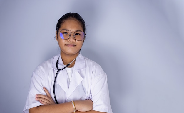 Portrait of a female doctor wearing glasses Standing with arms crossed on a white background.