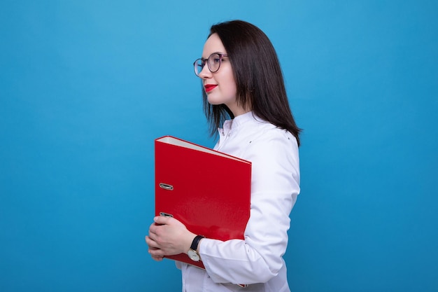 Portrait of a female doctor with a red folder on a blue background