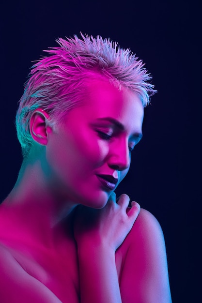 Portrait of female fashion model in neon light on dark.