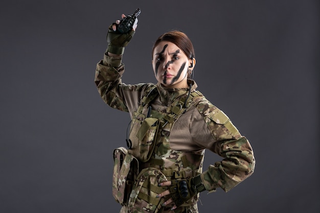 Portrait of female soldier with grenade in her hands on dark wall